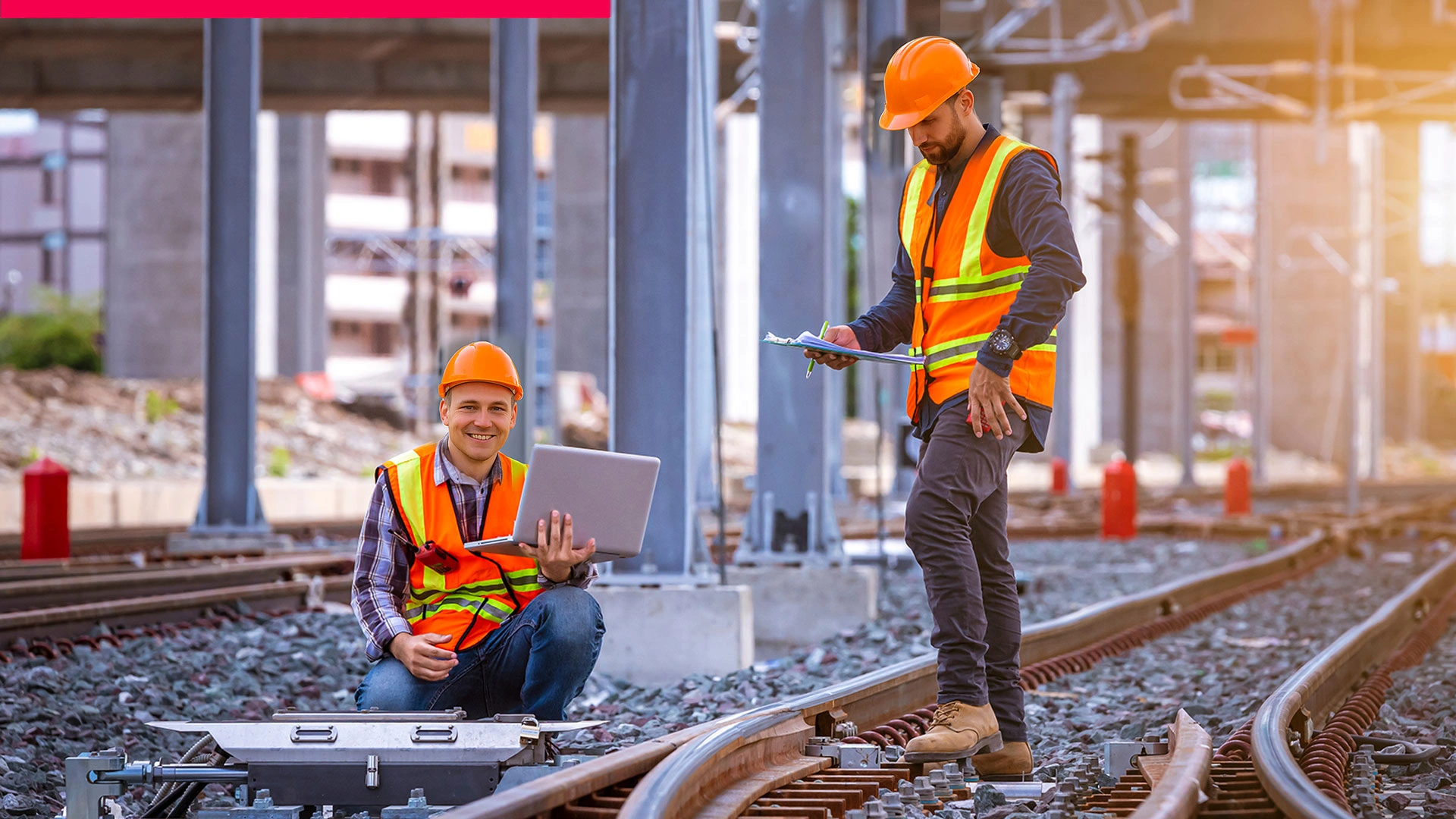 Two railway workers in safety vests and helmets inspect a track; one works with a laptop, the other with a clipboard – symbolising clear ROI and predictable costs.